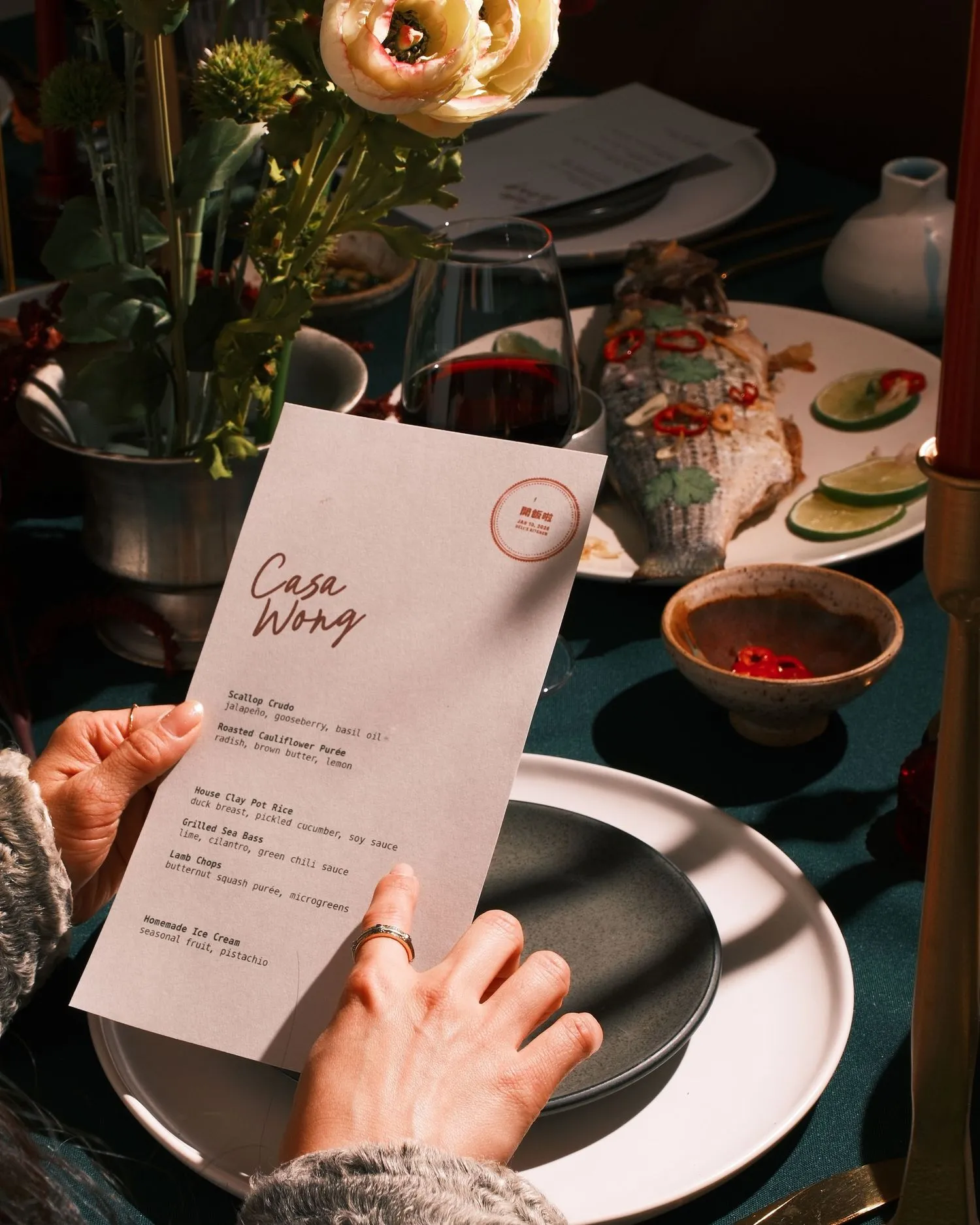 Hand holding the printed Casa Wong menu over the set table