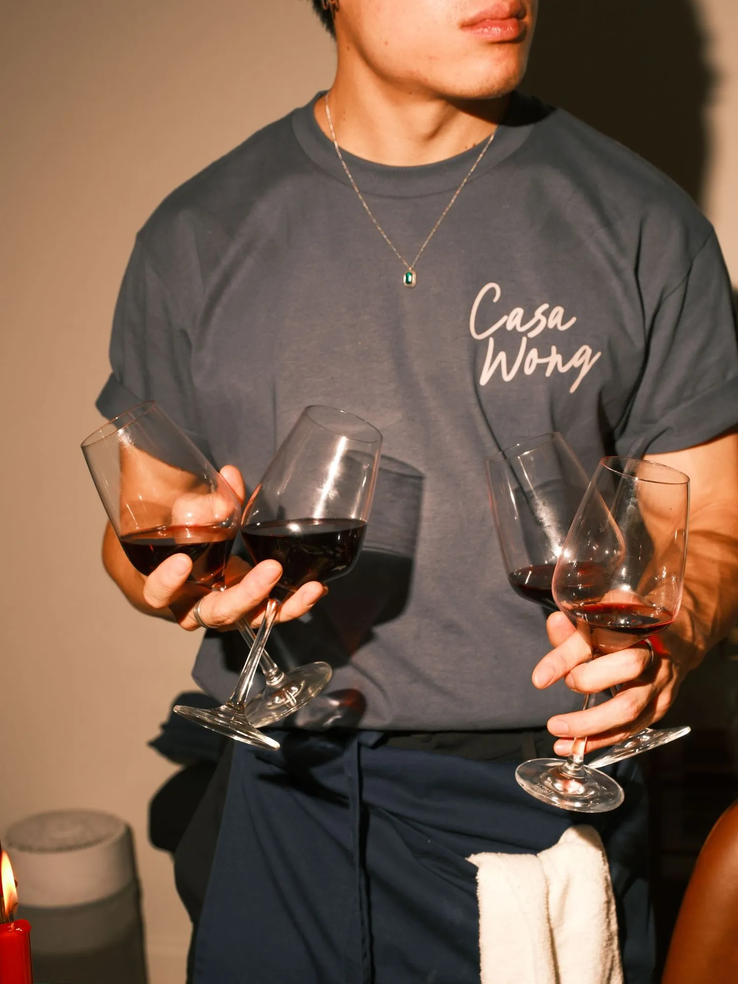 Guest in a Casa Wong tee holding two glasses of wine